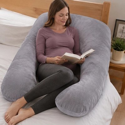 Coussin de grossesse gris suède entoure future maman qui lit bien assise