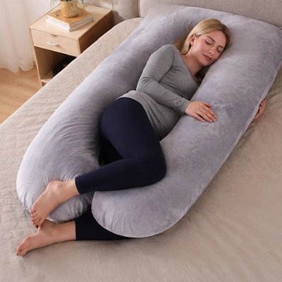 Coussin de grossesse gris suède entoure future maman qui se repose