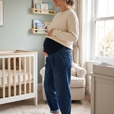 Pantalon grossesse bleu marine sur future maman dans la chambre de bébé